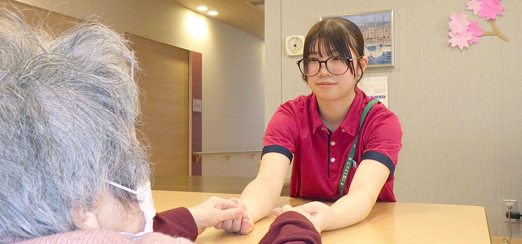 写真：入居者と手を取る職員